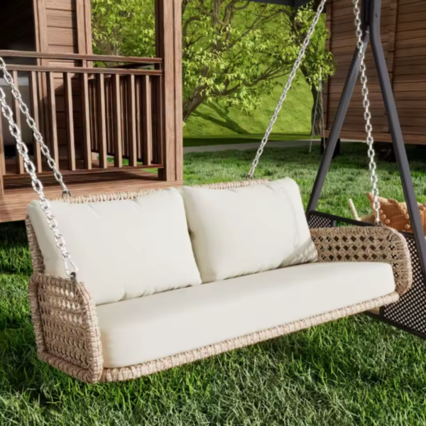 Fauteuil suspendu beige installé dans un jardin devant un chalet en bois.