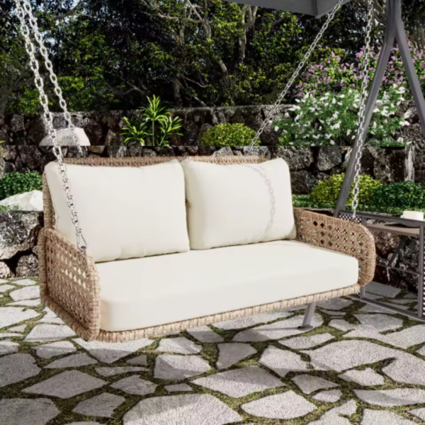 Fauteuil suspendu 2 places sur une terrasse en pierre entourée de fleurs.