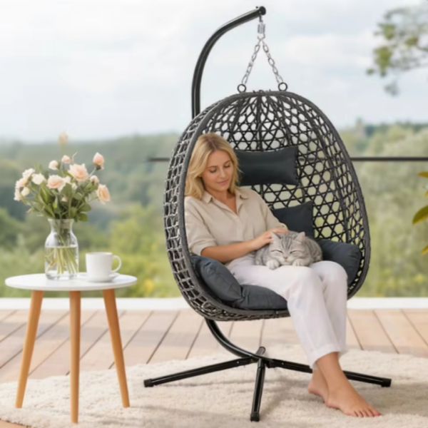 Jeune femme caressant un chat assise dans un fauteuil suspendu sur une terrasse.