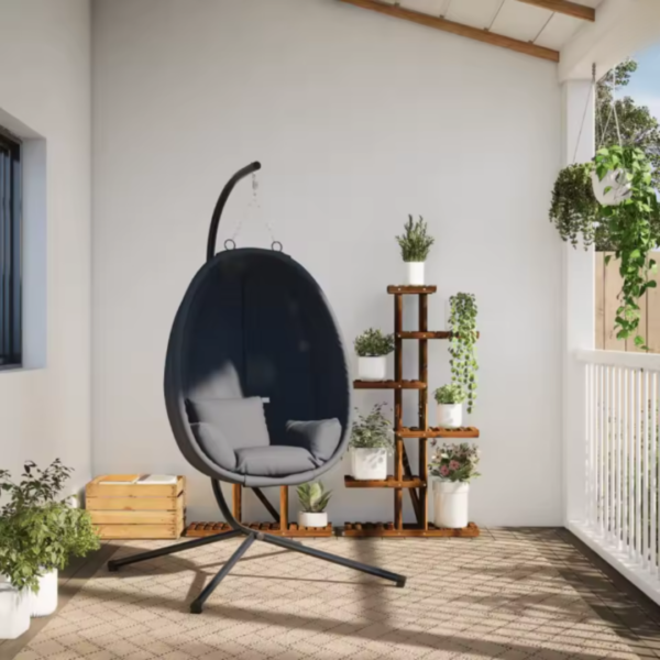Fauteuil suspendu installé sur une terrasse fleurie avec plantes vertes.